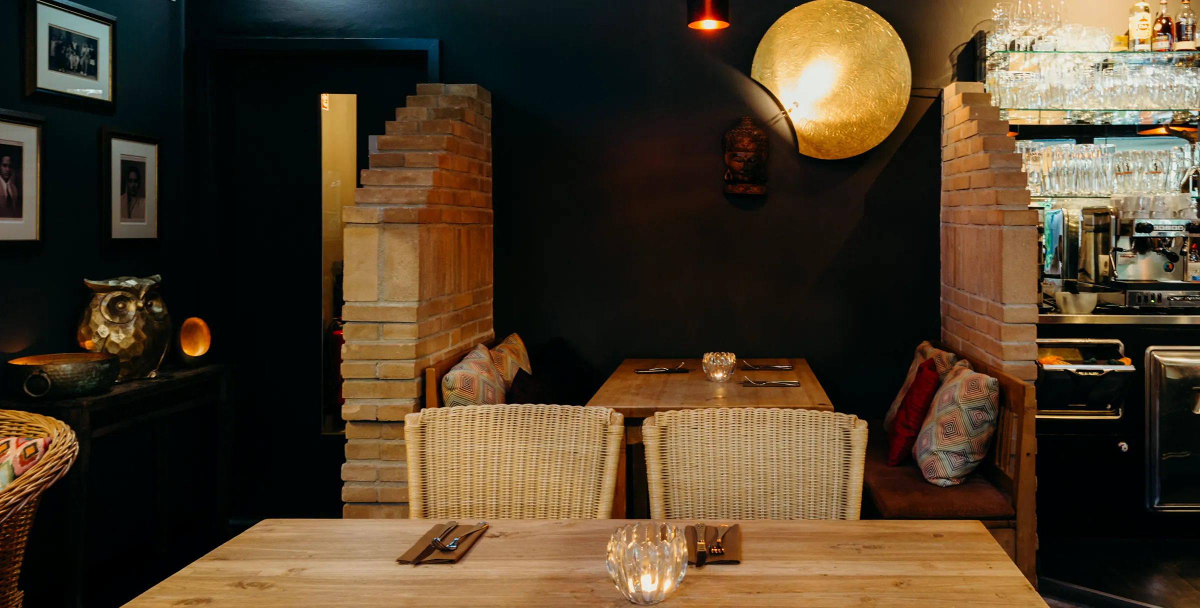 Kerzenbeleuchteter Speiseraum im Champor mit goldener Mondlampe, Backsteinsäulen und Rattanstühlen